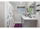 Bathroom featuring a shower, vanity with double sinks, dark fixtures, and a window bringing in natural light at 2522 N Roxboro St, Durham, NC 27704