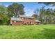 Expansive backyard view of a brick home featuring a well-manicured lawn and lush surrounding trees at 254 Pine Forest Dr, Siler City, NC 27344