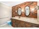 Rustic bathroom with brick accent wall, dual oval mirrors, and wooden vanity at 254 Pine Forest Dr, Siler City, NC 27344