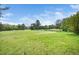 Scenic golf course view featuring a lush green fairway, mature trees, and a tranquil pond with clear blue sky at 254 Pine Forest Dr, Siler City, NC 27344
