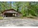 Covered carport and shed with a rustic design, surrounded by mature trees and flowering bushes at 254 Pine Forest Dr, Siler City, NC 27344