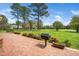 Brick patio with grill offers a view of a lush golf course, surrounded by trees and greenery at 254 Pine Forest Dr, Siler City, NC 27344