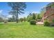 Brick patio adjoins lush yard overlooking green with mature trees and landscaping at 254 Pine Forest Dr, Siler City, NC 27344