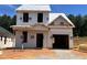 Image of a new two-story house construction with a garage and visible framing under a clear sky with trees in the background at 322 Bluejay St, Clayton, NC 27520
