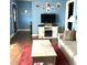 Cozy living room featuring a faux fireplace, mounted television and a red rug on the wood-look floors at 4159 Princeton Kenly Road, Kenly, NC 27542