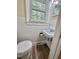 Small bathroom with white tile, pedestal sink, and modern toilet; features a window with natural light at 508 & 510 Gordon St, Roxboro, NC 27573