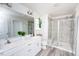 Bright bathroom featuring double vanity, large mirror, tiled shower, and wood-look flooring at 512 Oak Holly Ln, Zebulon, NC 27597
