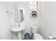 Cozy half-bathroom features a pedestal sink, toilet, decorative mirror and shelf at 512 Oak Holly Ln, Zebulon, NC 27597