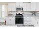 Well-lit kitchen features white cabinets, stainless steel appliances, and subway tile backsplash at 512 Oak Holly Ln, Zebulon, NC 27597
