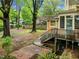 Backyard view featuring a brick patio, lush greenery, and stairs leading to a basement entrance at 524 S Boylan Ave, Raleigh, NC 27603