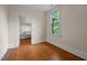 Empty bedroom with hardwood floors, natural light from the window, and an open closet space for storage at 524 S Boylan Ave, Raleigh, NC 27603