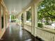 Spacious porch featuring dark wood floors, crisp white railings, and views of the lush, tree-lined street at 524 S Boylan Ave, Raleigh, NC 27603