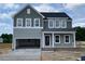 Charming two-story home featuring an open garage, gray siding, and a welcoming front porch with white columns at 54 Grove Township Way, Angier, NC 27501