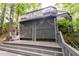 View of the home's exterior stairs and wooden deck, surrounded by lush trees at 6409 Lakeland Dr, Raleigh, NC 27612