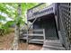 View of the home's exterior stairs and wooden deck, surrounded by lush trees at 6409 Lakeland Dr, Raleigh, NC 27612