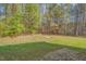 View of the yard, showcasing a potential firepit or garden area, and privacy trees at 709 Basil Dr, Durham, NC 27713