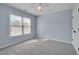 Light-filled bedroom with light blue walls, neutral carpet, window and a ceiling fan at 709 Basil Dr, Durham, NC 27713