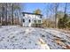 Backyard view featuring a deck with stairs and a spacious yard partially covered in snow surrounded by woods at 7218 Sunrise Rd, Chapel Hill, NC 27514