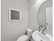Small bathroom featuring a round mirror, toilet, sink, and modern artwork at 7218 Sunrise Rd, Chapel Hill, NC 27514