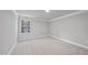 Bright bedroom featuring neutral carpet, crown molding, and a single large window with outdoor views at 7218 Sunrise Rd, Chapel Hill, NC 27514