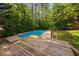 Backyard deck overlooking the pool featuring lush greenery and trees for privacy at 7433 Deer Track Dr, Raleigh, NC 27613