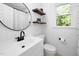 Modern bathroom features a sink, toilet, and shower with wood shelving for storage at 7433 Deer Track Dr, Raleigh, NC 27613