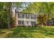 Inviting two-story home with a brick chimney, lush lawn, and mature trees creating a peaceful setting at 7433 Deer Track Dr, Raleigh, NC 27613
