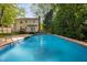 Backyard pool view surrounded by greenery and a view of the 2 story home at 7433 Deer Track Dr, Raleigh, NC 27613