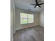 Bright bedroom with gray floors, ceiling fan, and a large window for natural light at 8013 River Water Ct, Raleigh, NC 27616