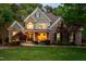 Charming stone and shake siding home featuring a welcoming front porch and meticulously landscaped front yard at twilight at 8480 Falkirk Ridge Ct, Wake Forest, NC 27587