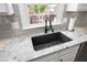 A close-up view of the kitchen sink with a black faucet, granite countertops, and gray backsplash at 8480 Falkirk Ridge Ct, Wake Forest, NC 27587