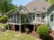Rear exterior featuring a screened porch and deck overlooking a well-maintained lawn and wooded area at 8480 Falkirk Ridge Ct, Wake Forest, NC 27587