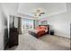 Spacious main bedroom featuring neutral walls, carpet, large windows, and a tray ceiling with ceiling fan at 85 Sun Mdw Cir, Benson, NC 27504
