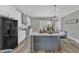 Spacious kitchen with a large island, white cabinets, a black refrigerator, and modern lighting fixtures at 1008 Holloway St, Durham, NC 27701