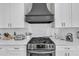 Stainless steel stove and range hood above with white countertops and white subway tile backsplash at 1008 Holloway St, Durham, NC 27701