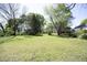 Wide backyard with green lawn, scattered trees, and surrounding greenery at 1015 Washington St, Burlington, NC 27217