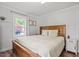 Cozy bedroom with a wood-framed bed, neutral decor, and a bright window overlooking the yard at 1017 Southerlund Rd, Garner, NC 27529