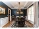 Elegant dining room with dark walls, tray ceiling, hardwood floors, and stylish light fixture at 10709 Thornbury Crest Ct, Raleigh, NC 27614