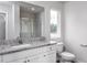 Bathroom vanity with granite countertops, white cabinets, a large mirror, and a glass-door shower at 11682 International Dr, Middlesex, NC 27557