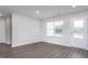 Bright living room featuring a large window, neutral walls, and stylish gray wood-look flooring at 11682 International Dr, Middlesex, NC 27557