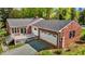 Aerial view of a red brick home featuring a two-car garage, deck, and well-maintained lawn at 118 Shannon Dr, Burlington, NC 27215