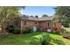 Back exterior featuring a red brick home with a green lawn, bushes, and HVAC system at 118 Shannon Dr, Burlington, NC 27215