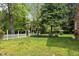 Sprawling backyard showcasing lush greenery, mature trees, and a charming white picket fence at 118 Shannon Dr, Burlington, NC 27215