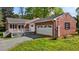 Exterior view of a red brick home featuring a two-car garage, deck, and well-maintained lawn at 118 Shannon Dr, Burlington, NC 27215