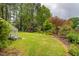 Large, grassy backyard with mature trees, playground set, and stairs leading to the deck at 1809 Green Ford Ln, Apex, NC 27502