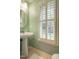 Bright bathroom with a pedestal sink, updated fixtures, and natural light from shuttered window at 1809 Green Ford Ln, Apex, NC 27502