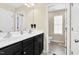 Bright bathroom featuring double sinks with dark cabinetry, large mirrors, and an adjoining toilet area at 1919 Sinclair Trce, Burlington, NC 27215