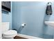Powder room featuring a blue wall with a toilet, sink, and storage at 1919 Sinclair Trce, Burlington, NC 27215