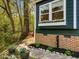Close-up of a home's exterior featuring blue siding, brick foundation, flower boxes, and landscaping at 209 Dickens Dr, Raleigh, NC 27610