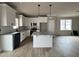 Bright kitchen featuring white cabinets, a granite island with pendant lighting, and stainless steel appliances at 244 Bluejay St, Clayton, NC 27520